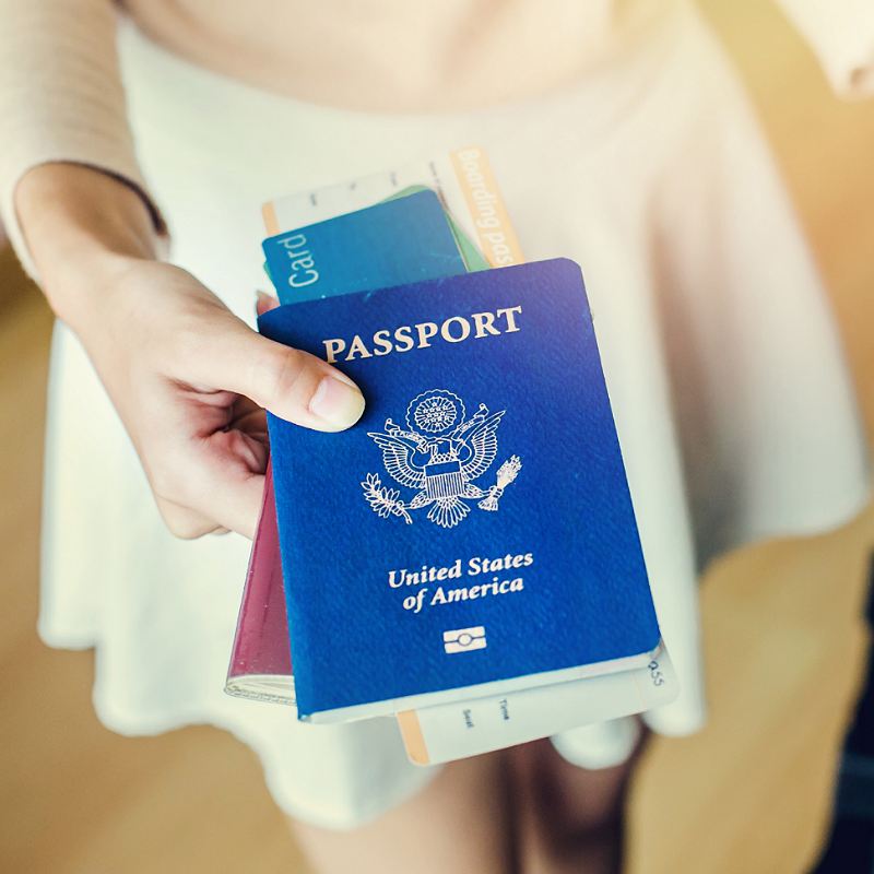 Female Traveler Holding A U.S. American Passport And A Boarding Gate Ahead Of International Travel