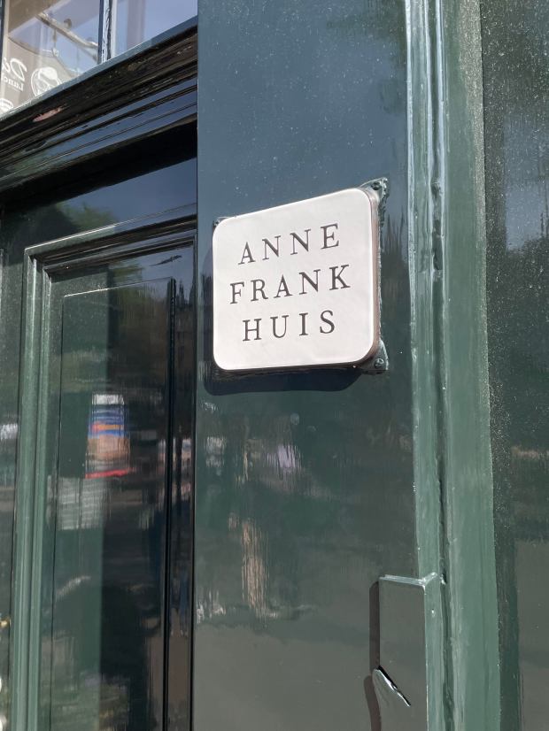 A small sign indicates the outside of the Anne Frank House in Amsterdam.